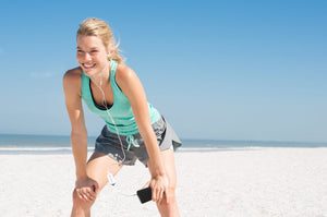 Woman resting after beach workout with phone and earbuds