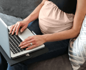 Pregnant woman working on laptop with belly band
