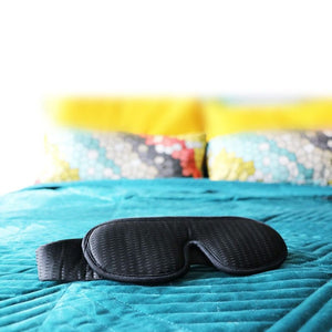 Black sleep mask on teal bed