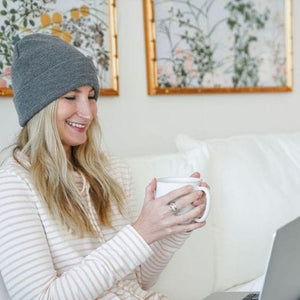 Woman in Def8208 beanie with coffee and laptop