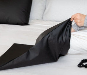 EA3017_2 Black bed sheet being held over white bedding