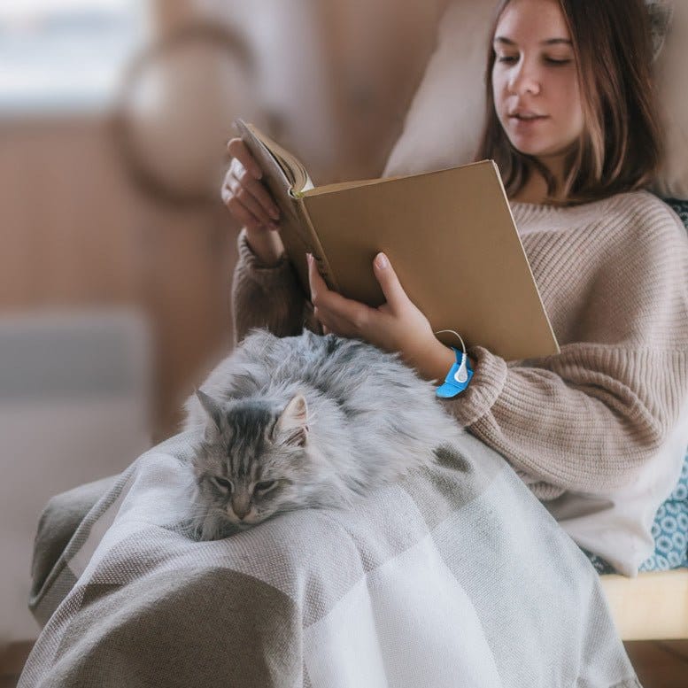 Woman reading book with cat on lap