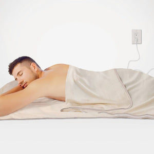 Man sleeping under blanket, plugged into wall