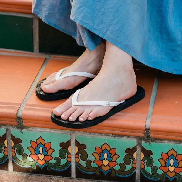 Black and white grounding flip flops on woman's feet