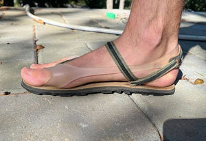 Foot wearing a sandal on a stone surface.
