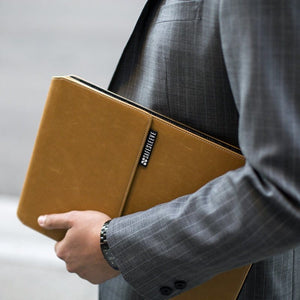 Safesleeve tan laptop case held by businessman