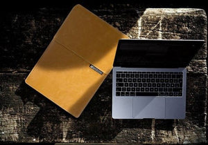 Tan laptop cover and laptop on wood surface