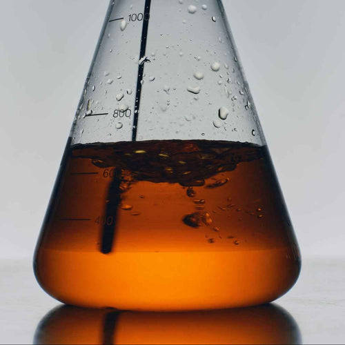 Conical flask with brown liquid on a gray background