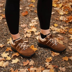 Woman wearing brown leather trail shoes in fall leaves