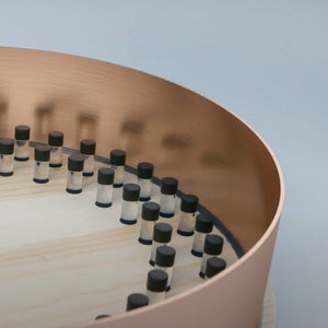 Array of vials in a circular wooden and copper structure.